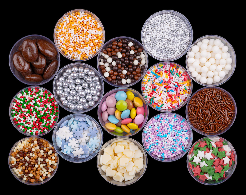 Variety of colorful sprinkles and candy toppings in small round containers