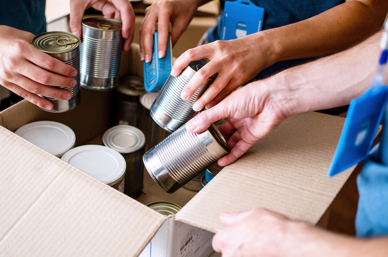 Volunteers placing canned goods into a donation box