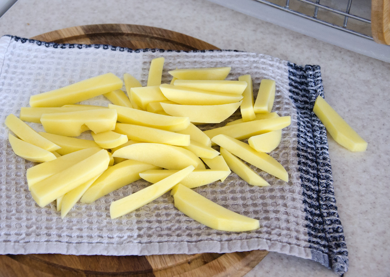 Raw potato fries laid out on a towel before cooking