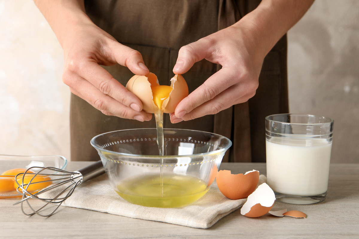 baker cracking egg over bowl