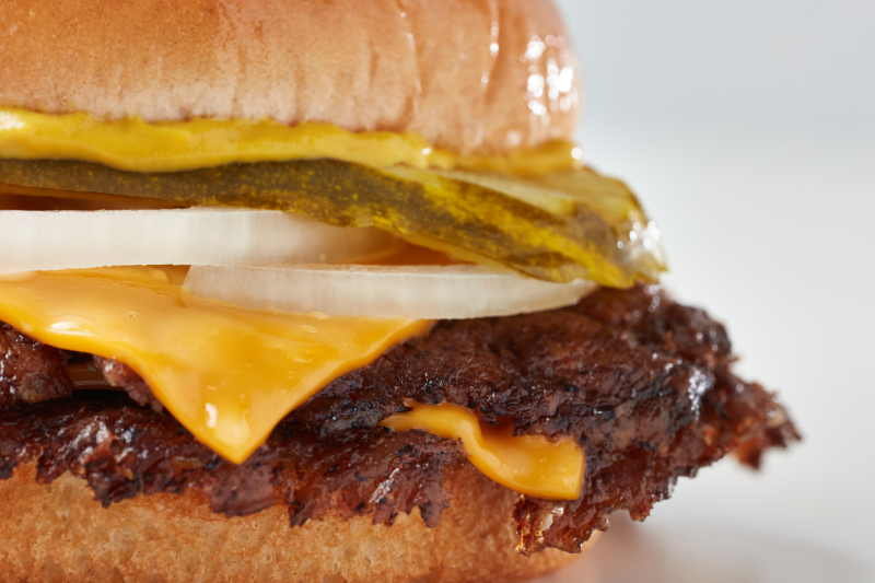 Close-up of a Freddy’s Original Double Steakburger with cheese, pickles, onions, and mustard