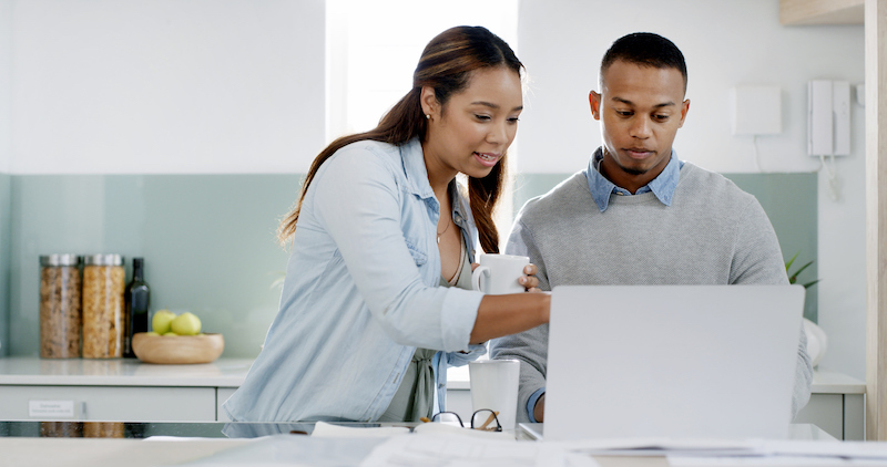 Two people reviewing plans on a laptop in a kitchen