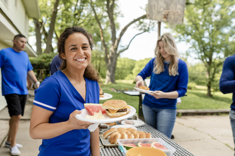 People serving themselves food at an outdoor group burger catering meal