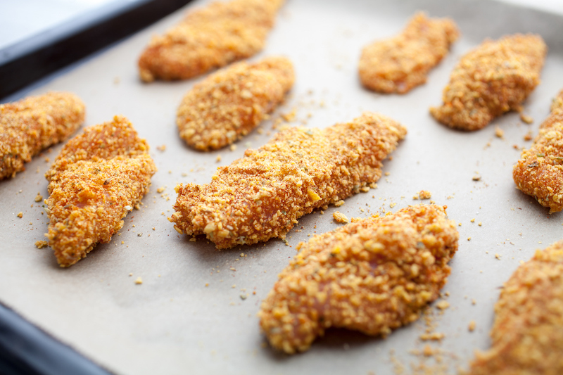 Breaded chicken tenders on a baking sheet