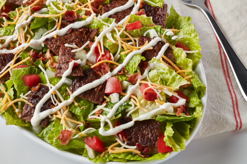 Freddy’s Steakburger Bowl with lettuce, cheese, tomatoes, bacon, and creamy dressing