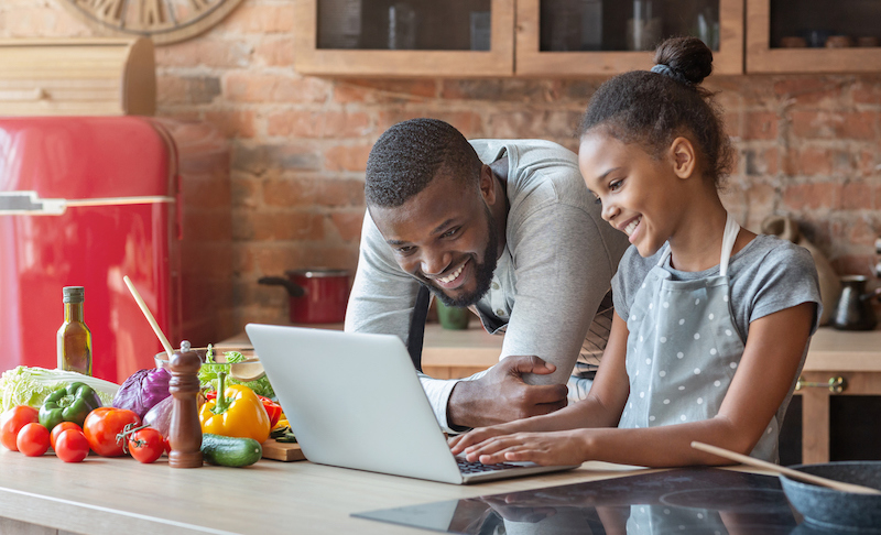 man and young girl looking at recipe in kitchen