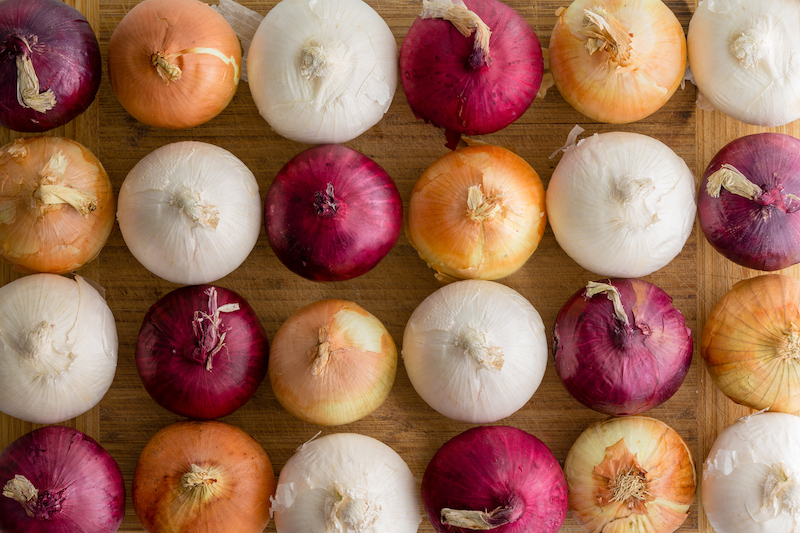 Variety of whole onions arranged on a cutting board