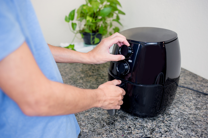 Person adjusting settings on a black air fryer