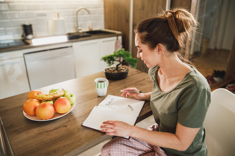 Woman writing a to-do list at a kitchen table