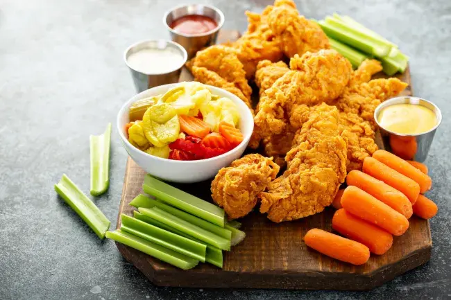 Fried chicken tenders with celery, carrots, pickled vegetables, and dipping sauces