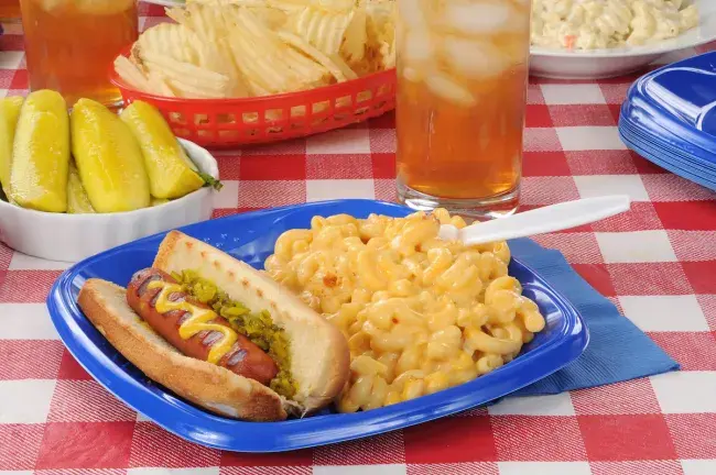 Hot dog with mustard and relish served with macaroni and cheese and iced tea
