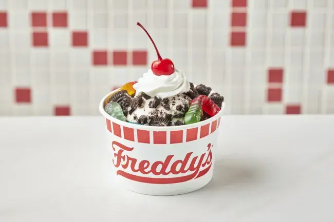 Freddy’s Dirt &amp; Worms kids sundae with crushed OREO® cookies, gummy worms, whipped cream, and a cherry