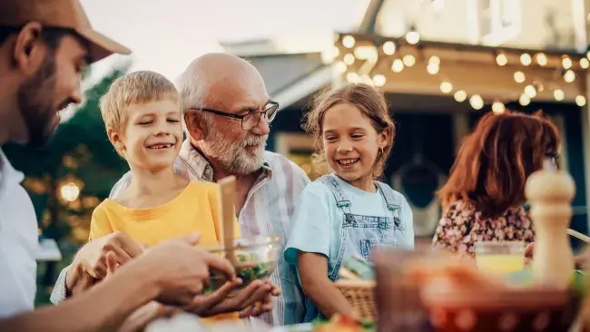Family enjoying an outdoor meal together in the backyard under string lights