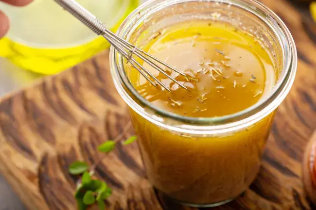Whisked marinade in a glass jar on a wooden surface