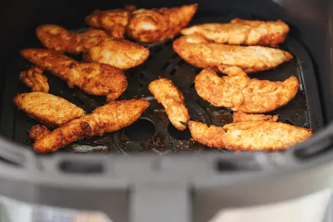 Chicken tenders cooking in an air fryer