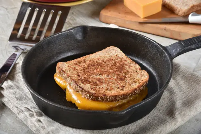 Grilled cheese sandwich cooking in a cast iron skillet