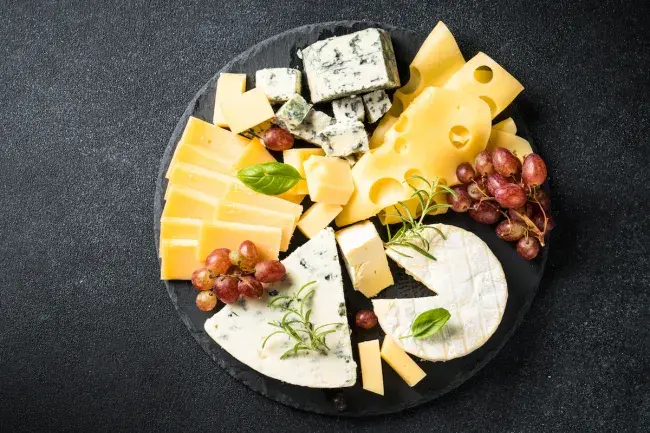 Assorted cheeses with grapes and herbs on a platter