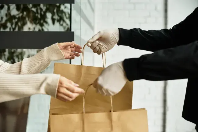 Person handing takeout bags to a customer