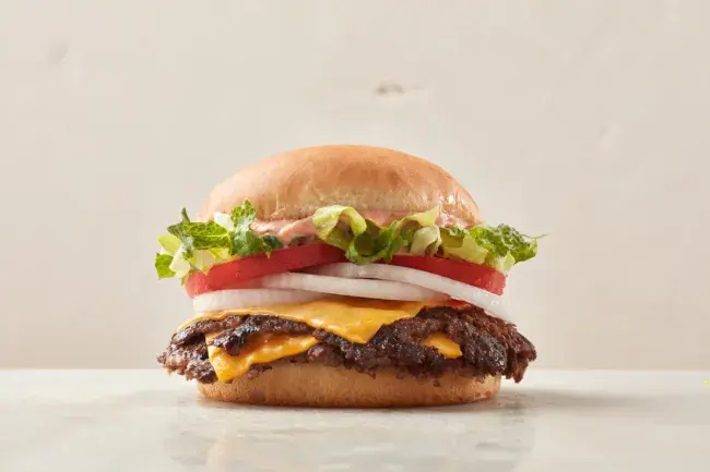 Freddy’s California Style Steakburger topped with lettuce, tomato, onion, and signature sauce