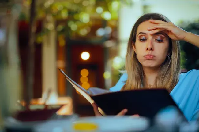 Person looking at a restaurant menu while deciding what to order