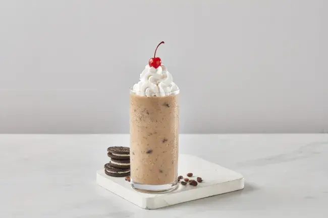 Freddy's Cookies &amp; Crème Latte Shake topped with whipped cream and a cherry