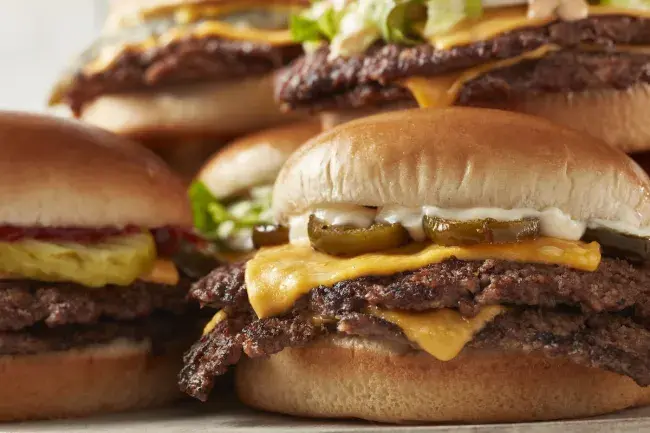 Assortment of steakburgers with melted cheese and assorted toppings