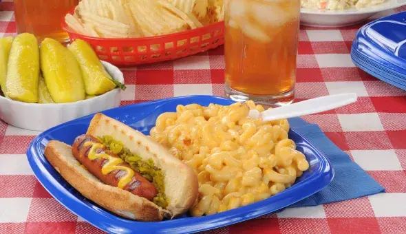 Hot dog with mustard and relish served with macaroni and cheese and iced tea