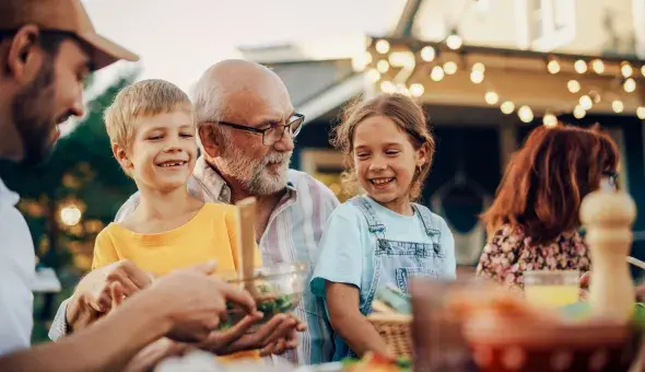 Family enjoying an outdoor meal together in the backyard under string lights