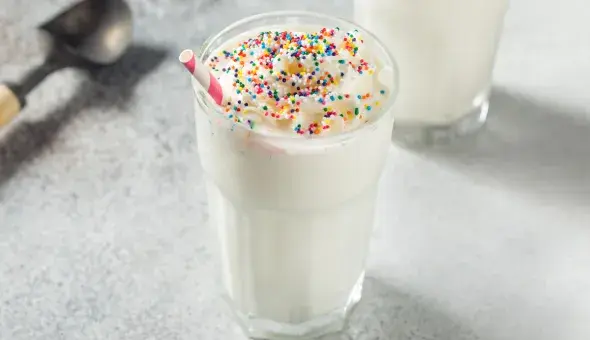 Vanilla milkshake topped with whipped cream and colorful sprinkles