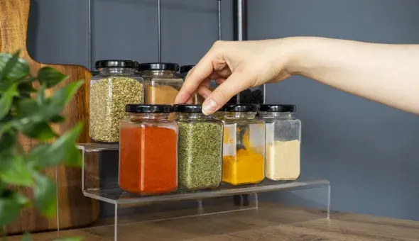 Hand reaching for a spice jar on a kitchen shelf