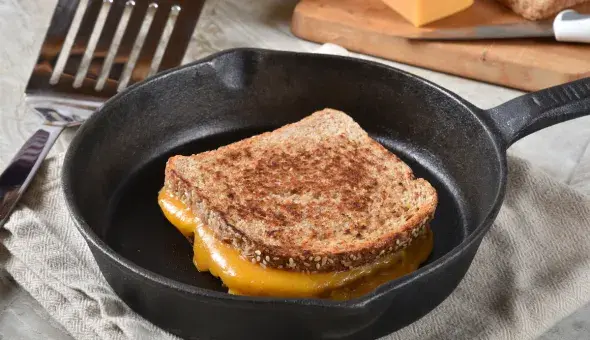 Grilled cheese sandwich cooking in a cast iron skillet