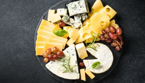 Assorted cheeses with grapes and herbs on a platter