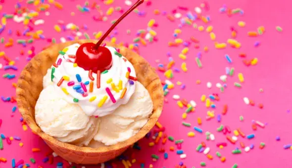 Vanilla ice cream in a waffle bowl with sprinkles and a cherry