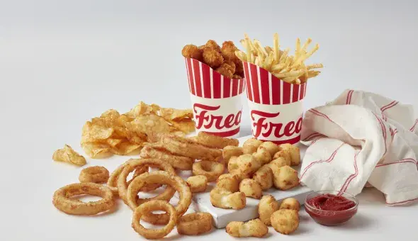Freddy’s sides including fries, onion rings, cheese curds, chips, and tots with ketchup