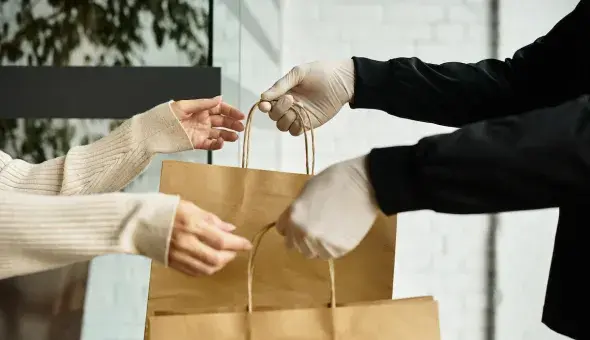 Person handing takeout bags to a customer