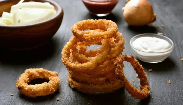 Stack of crispy onion rings with dipping sauces