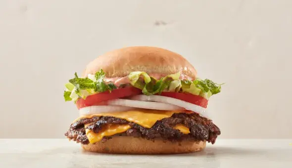 Freddy’s California Style Steakburger topped with lettuce, tomato, onion, and signature sauce