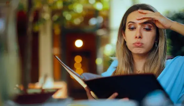 Person looking at a restaurant menu while deciding what to order