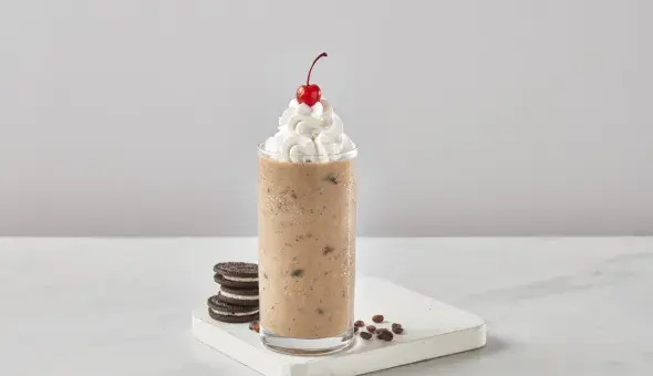 Freddy's Cookies &amp; Crème Latte Shake topped with whipped cream and a cherry