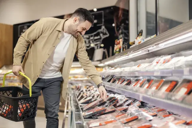 man looking at meat options at a grocery store